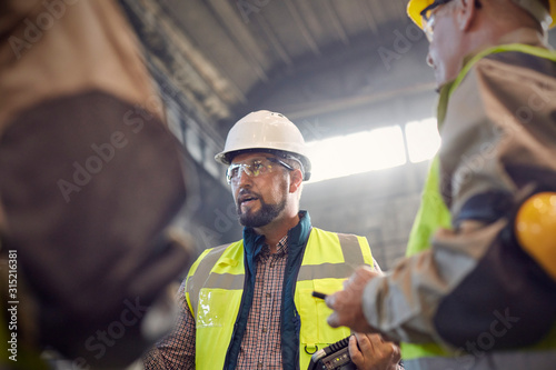 Supervisor talking to steelworkers in steel mill