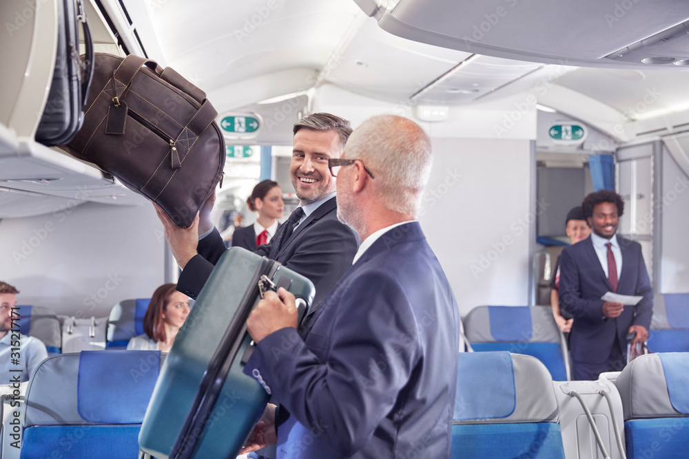 Businessmen loading luggage into storage compartment on airplane Businessmen loading luggage into storage compartment on airplane