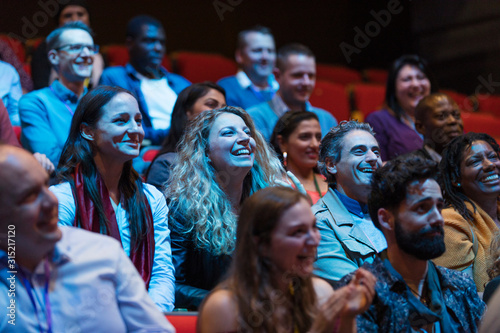 Smiling, enthusiastic audience in dark auditorium photo