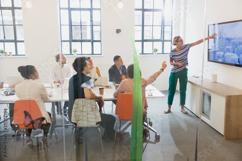 Female architect at television screen leading conference room meeting