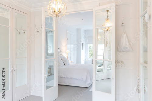 White, luxury home showcase interior bedroom French doors chandelier