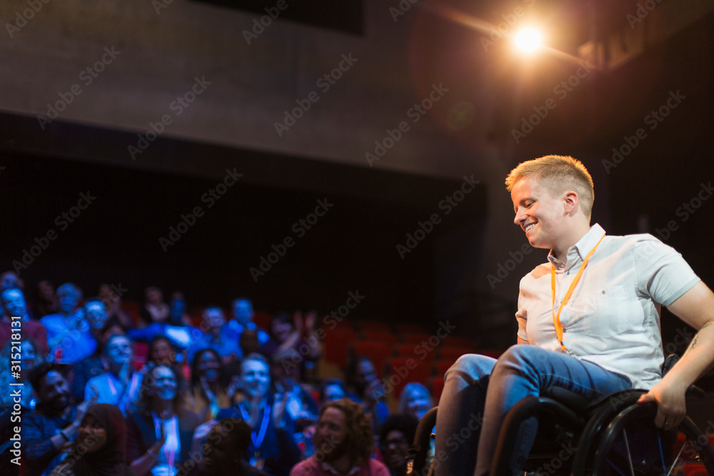 © Sam Edwards/Caia Image - Smiling female speaker in wheelchair on stage
