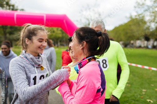 Daughter placing medal around neck of mother at charity run in park