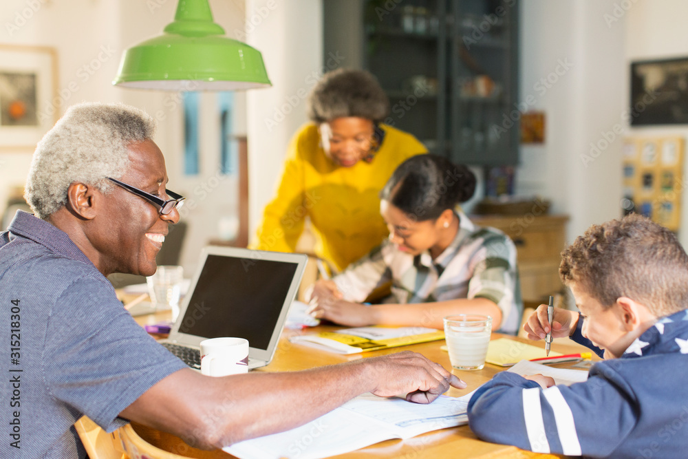 Grandfather helping grandson with homework at dining table Grandfather helping grandson with homework at dining table