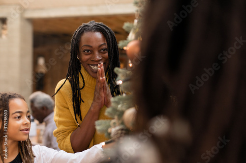 Smiling, grateful mother decorating Christmas tree with daughters