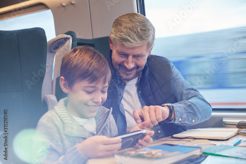 Father and son using smart phone on passenger train photo