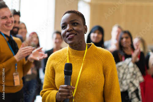 Smiling businesswoman speaker with microphone at conference