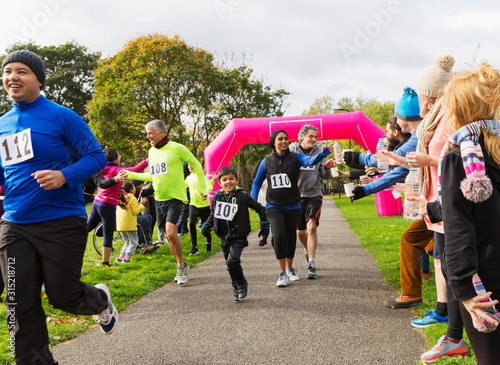 Runners reaching for water, running at charity run in park