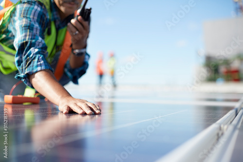 Engineer with walkie-talkie inspecting solar panels at power plant