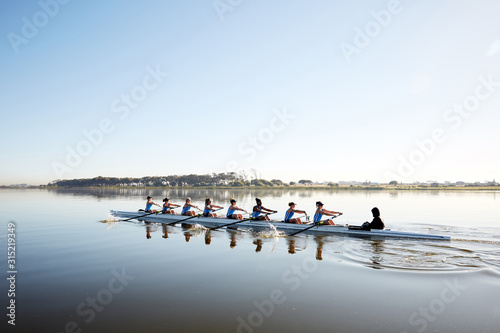 Female rowing team rowing scull on tranquil lake photo