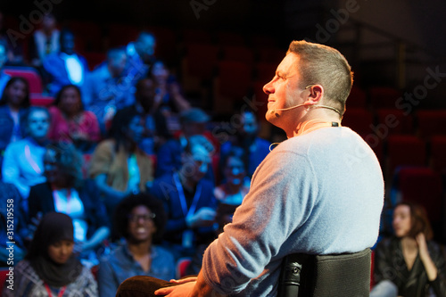 Smiling male speaker in wheelchair on stage photo