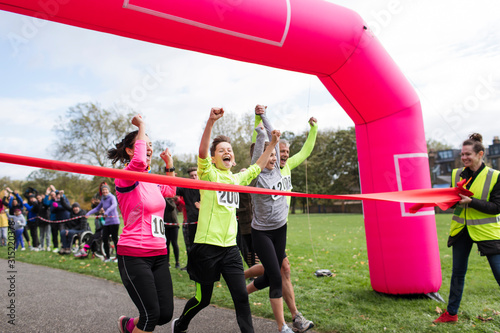 Enthusiastic family runners crossing charity run finish line in park