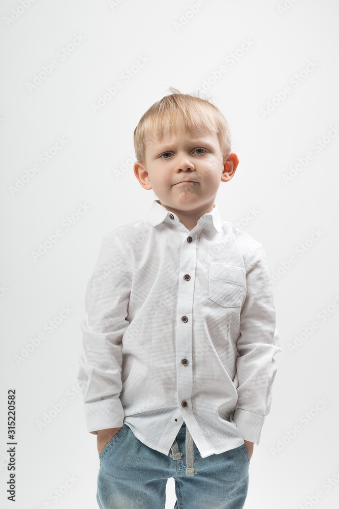 Portrait of a stylish and fashionable charismatic boy, frowning and serious in a white shirt on a white background. Portrait of a stylish and fashionable charismatic boy, frowning and serious in a white shirt on a white background.