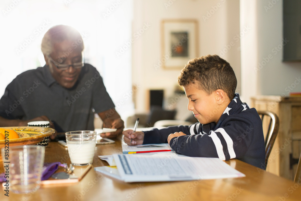 Grandfather at table with grandson doing homework Grandfather at table with grandson doing homework