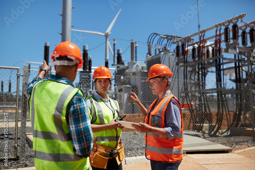 Engineers with digital tablet at sunny power plant