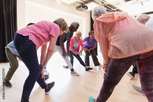 Active seniors stretching legs in exercise class photo