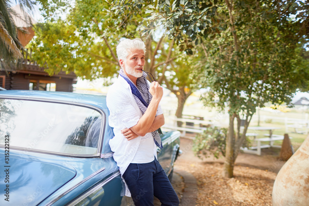 Portrait confident man biting tip of eyeglasses at car Portrait confident man biting tip of eyeglasses at car