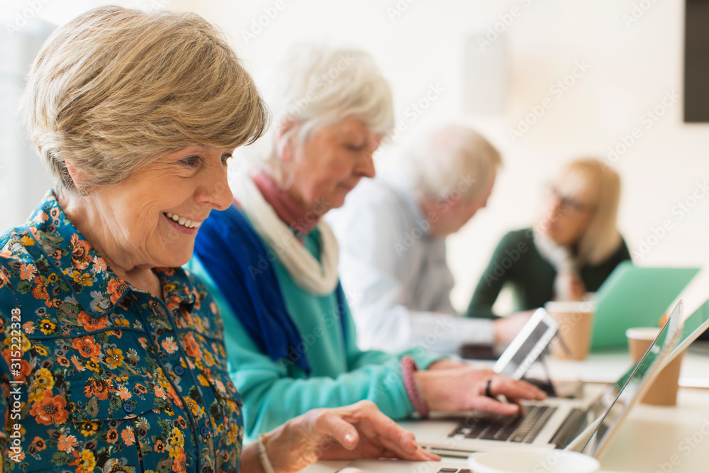 Senior women using laptops in conference room meeting Senior women using laptops in conference room meeting