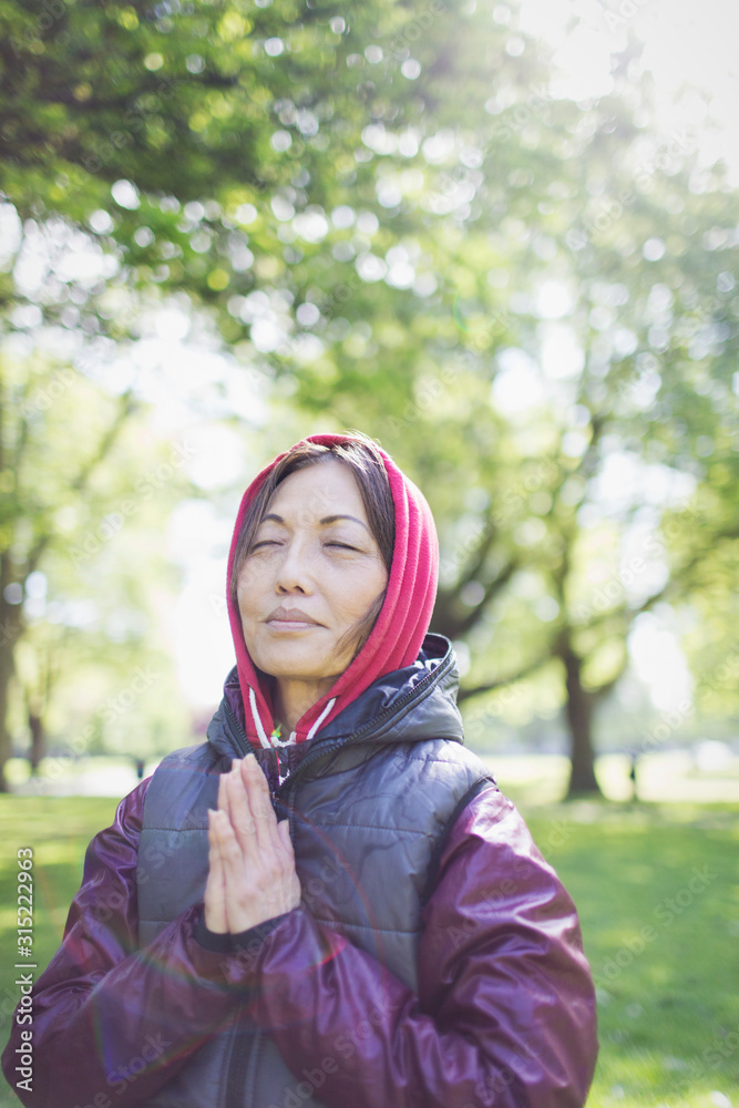 Serene active senior woman meditating in sunny park