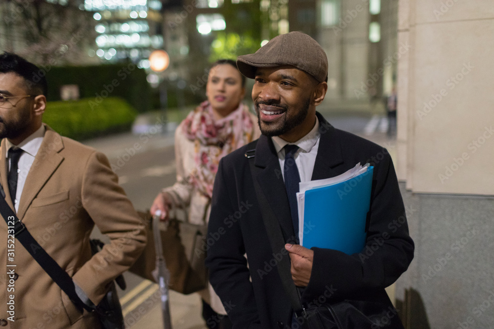 Smiling businessman walking on urban sidewalk at night Smiling businessman walking on urban sidewalk at night