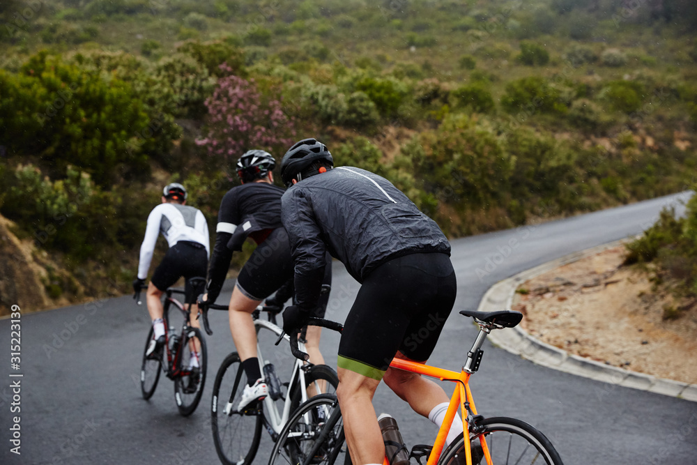 Male cyclists cycling uphill on road Male cyclists cycling uphill on road