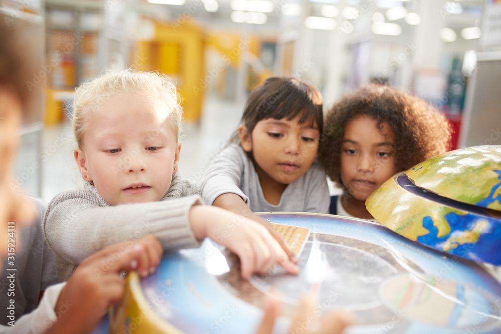 Curious kids at interactive globe exhibit in science center Curious kids at interactive globe exhibit in science center