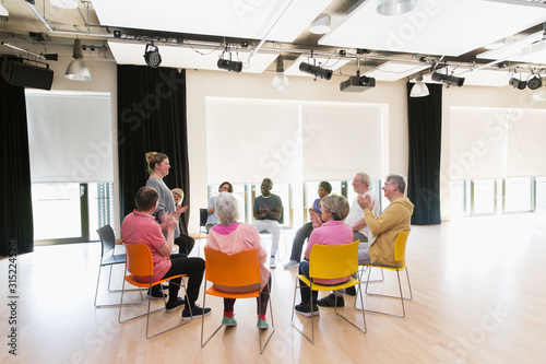 Active seniors clapping for instructor in circle in community center