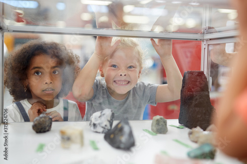 Silly girl making a face at rock exhibit display case in science center