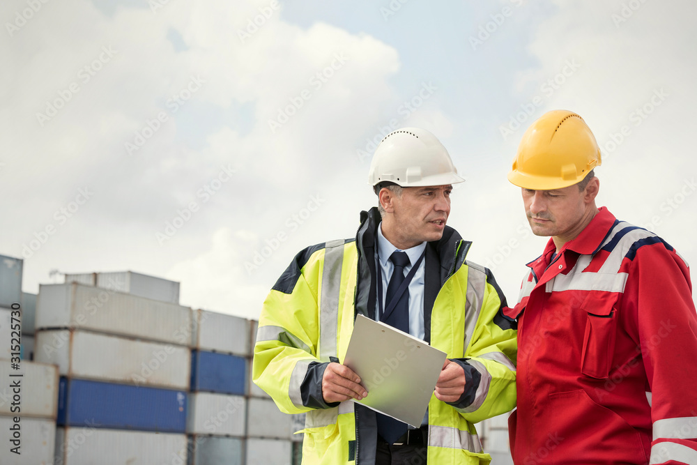 Dock worker and manager with clipboard talking at shipyard Dock worker and manager with clipboard talking at shipyard
