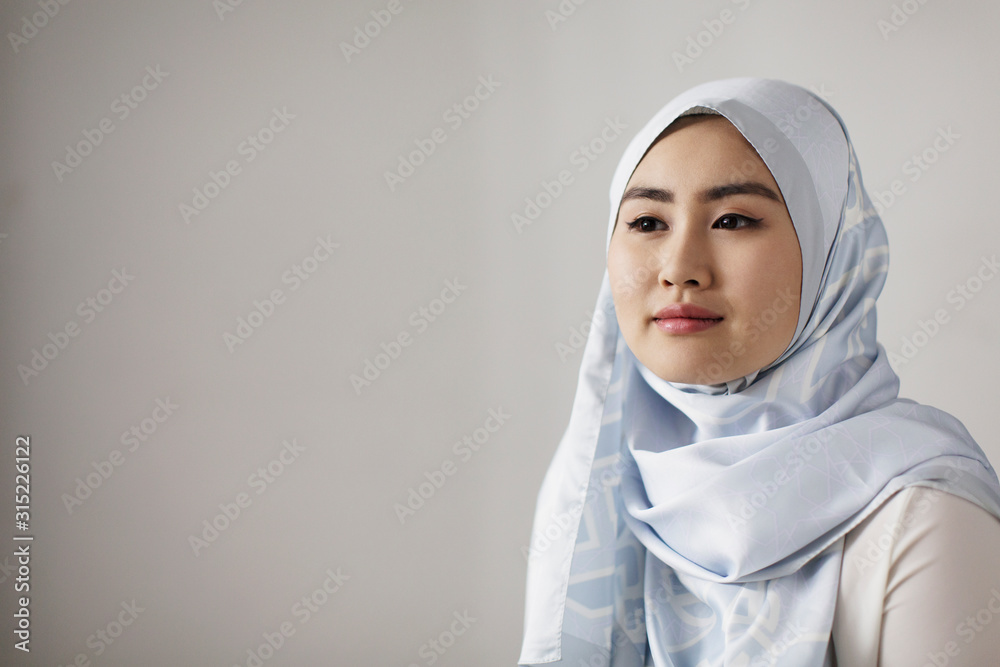 Portrait serene young woman in blue silk hijab looking away Portrait serene young woman in blue silk hijab looking away