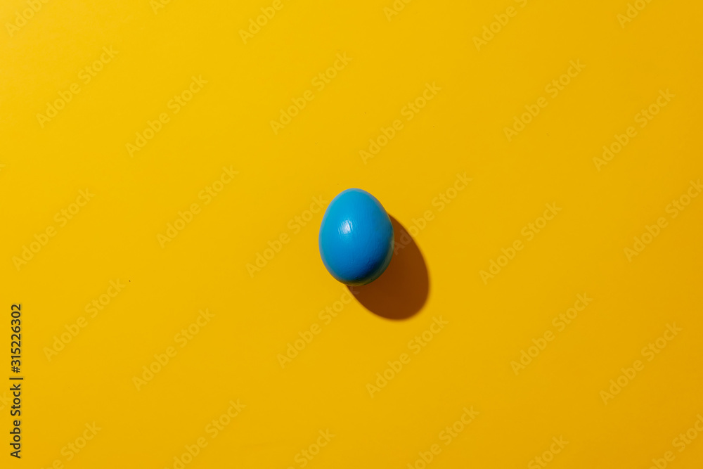 View on blue Easter egg on yellow background View on blue Easter egg on yellow background