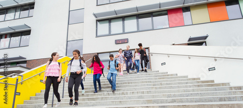 Junior high students leaving school building, descending steps