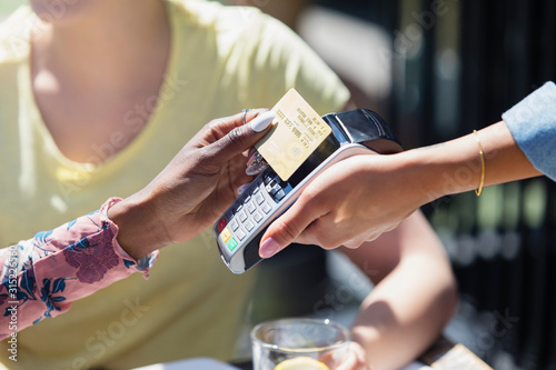 Woman paying waitress with smart card photo