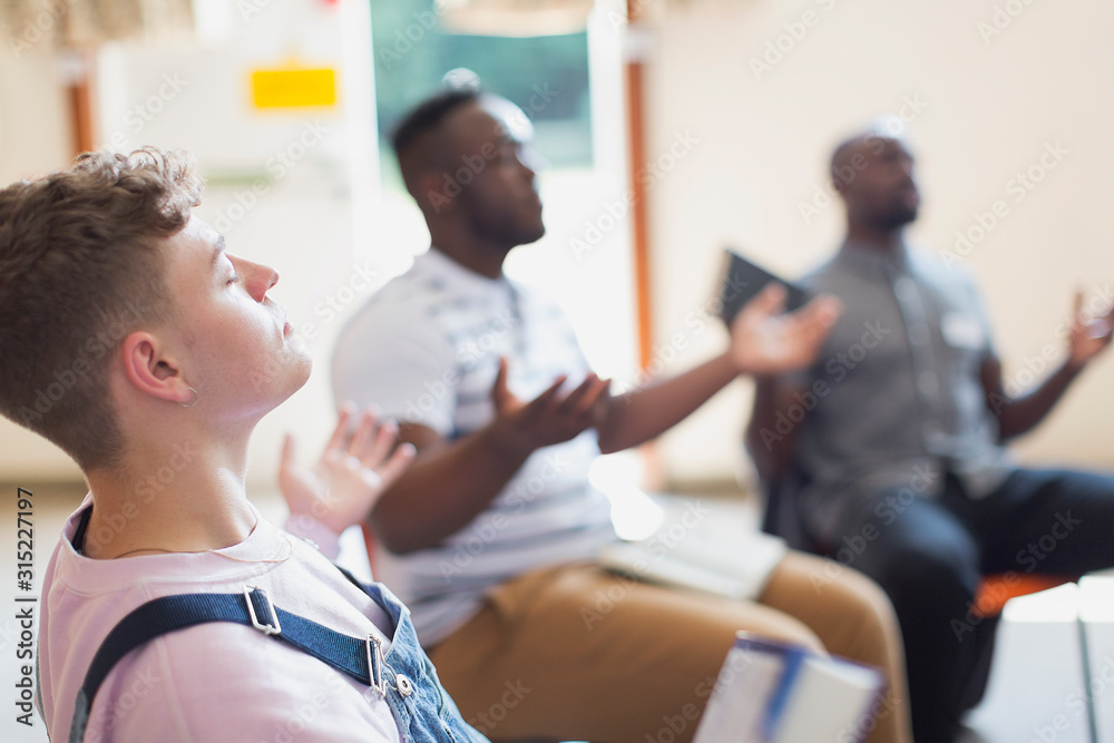 Serene man praying with arms outstretched in prayer group