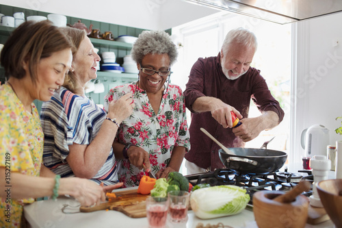 Active senior friends cooking in kitchen