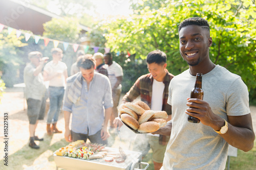 Portrait confident young man drinking beer, enjoying barbecue in summer backyard