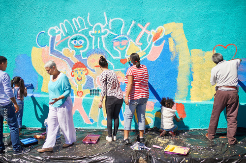 Community volunteers painting vibrant mural on sunny wall