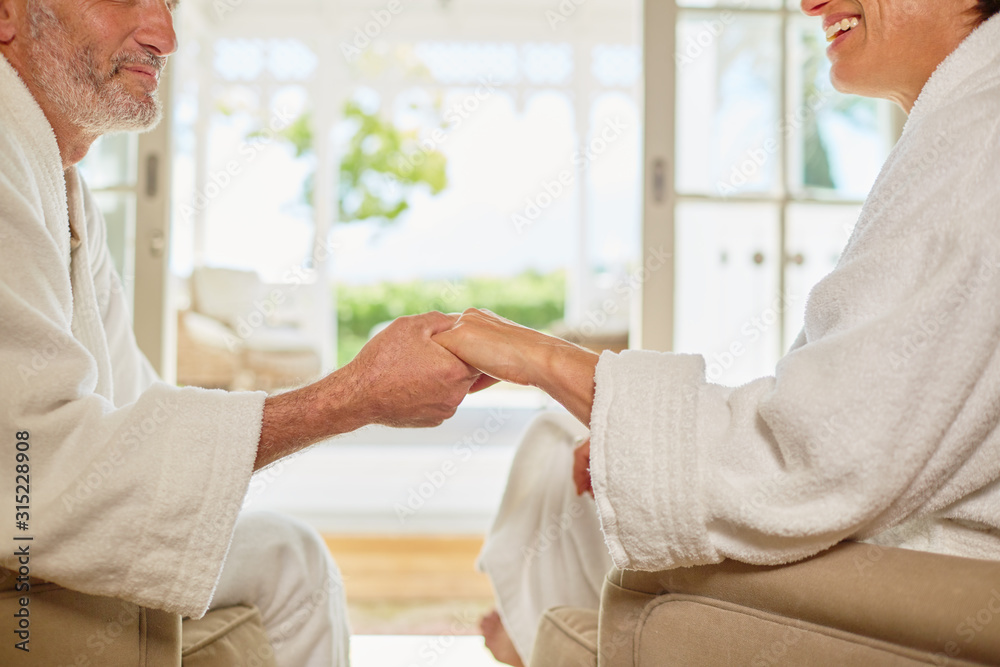 Affectionate couple in spa bathrobes holding hands Affectionate couple in spa bathrobes holding hands