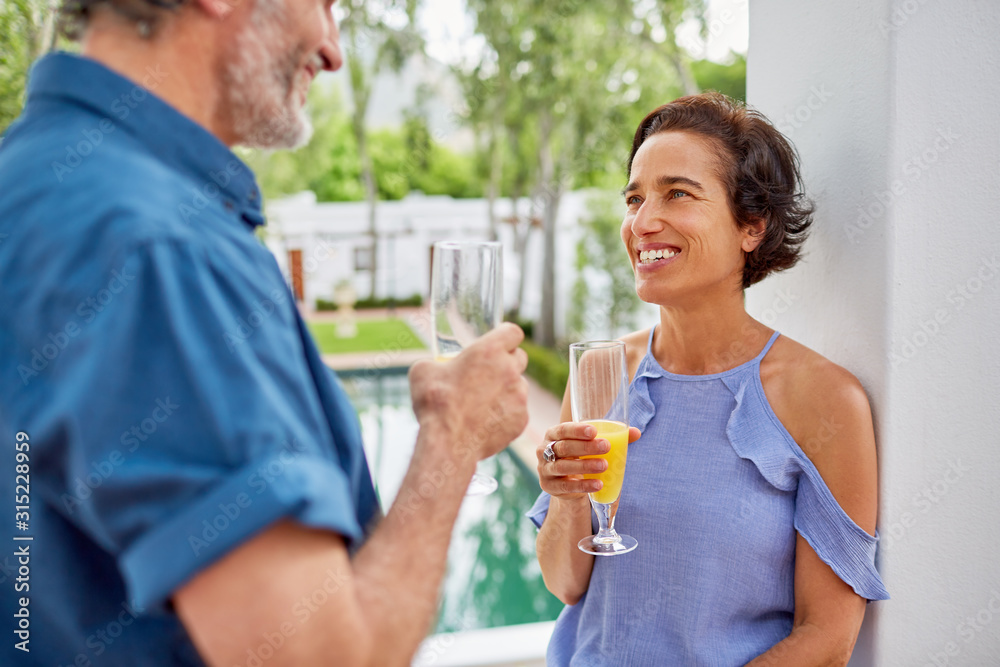 Happy mature couple drinking mimosas on hotel balcony