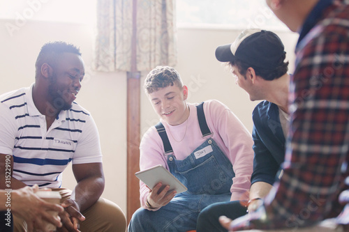 Men with digital tablet talking in group therapy photo