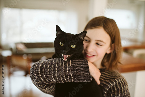 Portrait girl holding hissing black cat photo