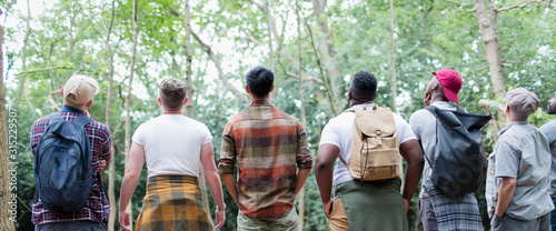 Mens group hiking, standing in a row and bird watching in woods photo