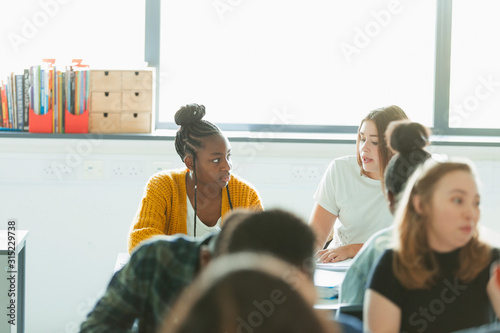 High school girl students talking, doing homework in classroom