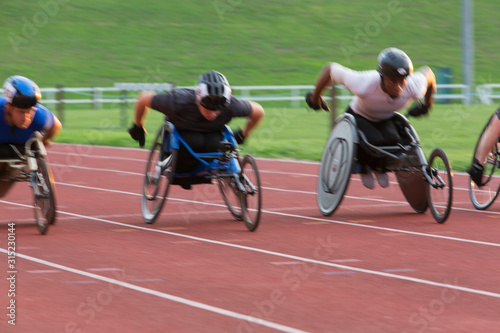 Determined paraplegic athlete speeding along sports track in wheelchair race photo