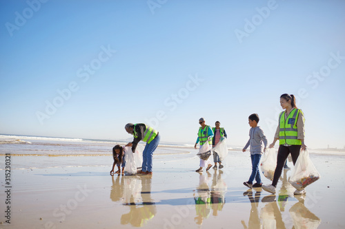 Volunteers cleaning litter from wet sand beach