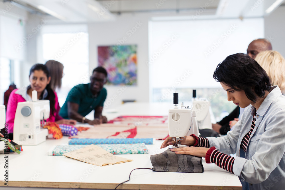 Fashion design students working at sewing machines in studio Fashion design students working at sewing machines in studio