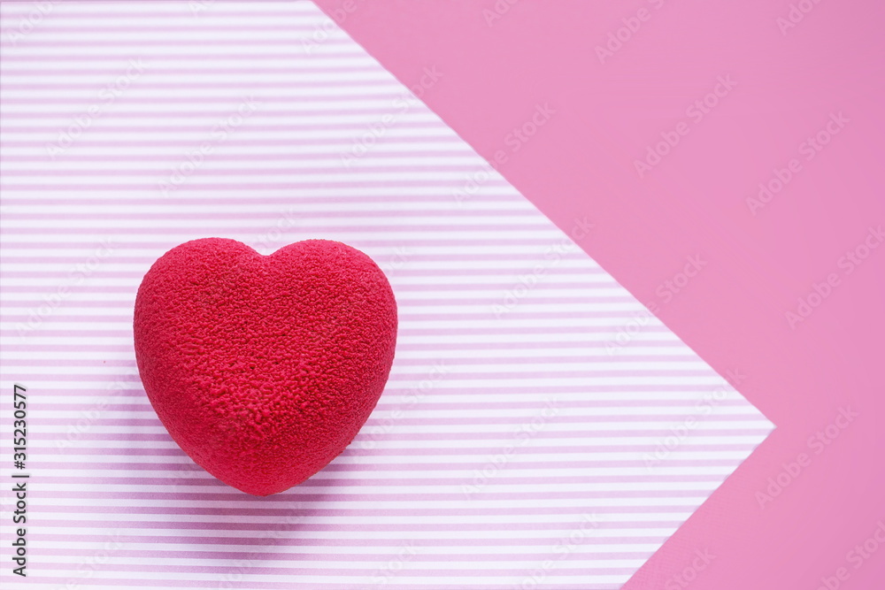 Valentines day concept. Pink velvet heart shaped cake on on a pink striped surface. 