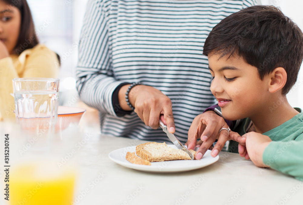 Mother cutting crusts off bread for son Mother cutting crusts off bread for son