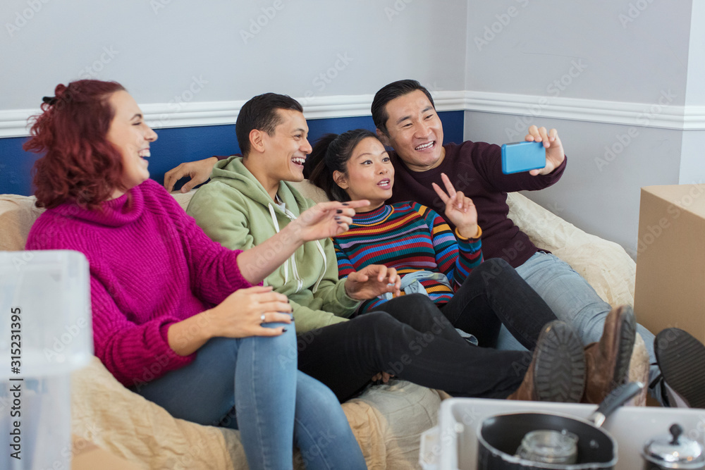 Happy friends taking a break from moving, taking selfie on sofa Happy friends taking a break from moving, taking selfie on sofa