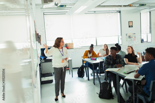 High school students watching teacher leading lesson at whiteboard in classroom photo